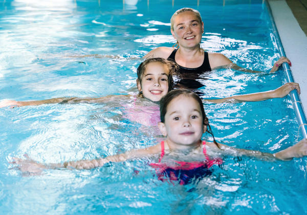 Mother With Two Daughters Having Fun In Indoor Swimming-pool. Gi